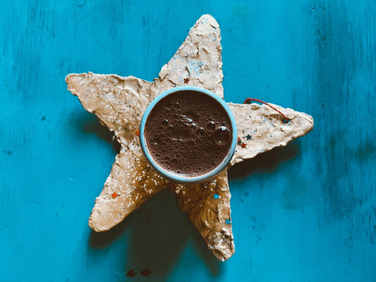 Cacao ceremonial sobre creación infantil, estrella de papel maché sobre escritorio azul