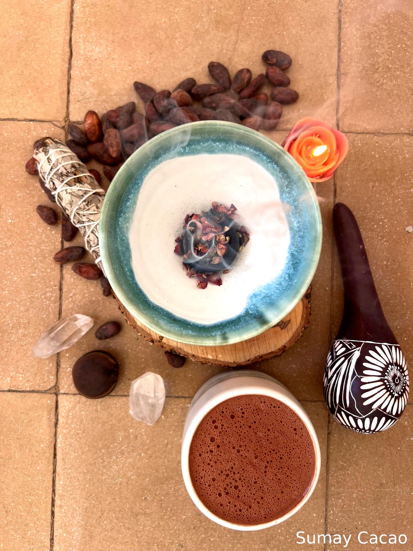 Copalera encendida con atado de salvia, semillas de cacao, sonaja, vela, cuarzo, y taza de cacao