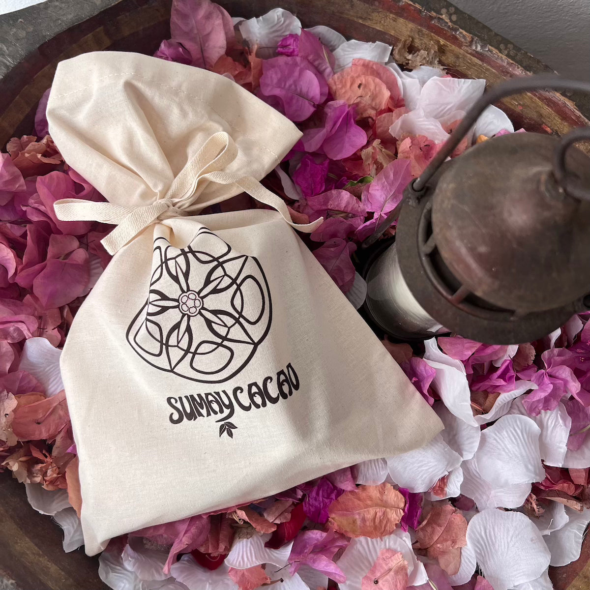 Bolsa de algodón natural de Sumay Cacao sobre lecho de flores rosas y pétalos blancos.