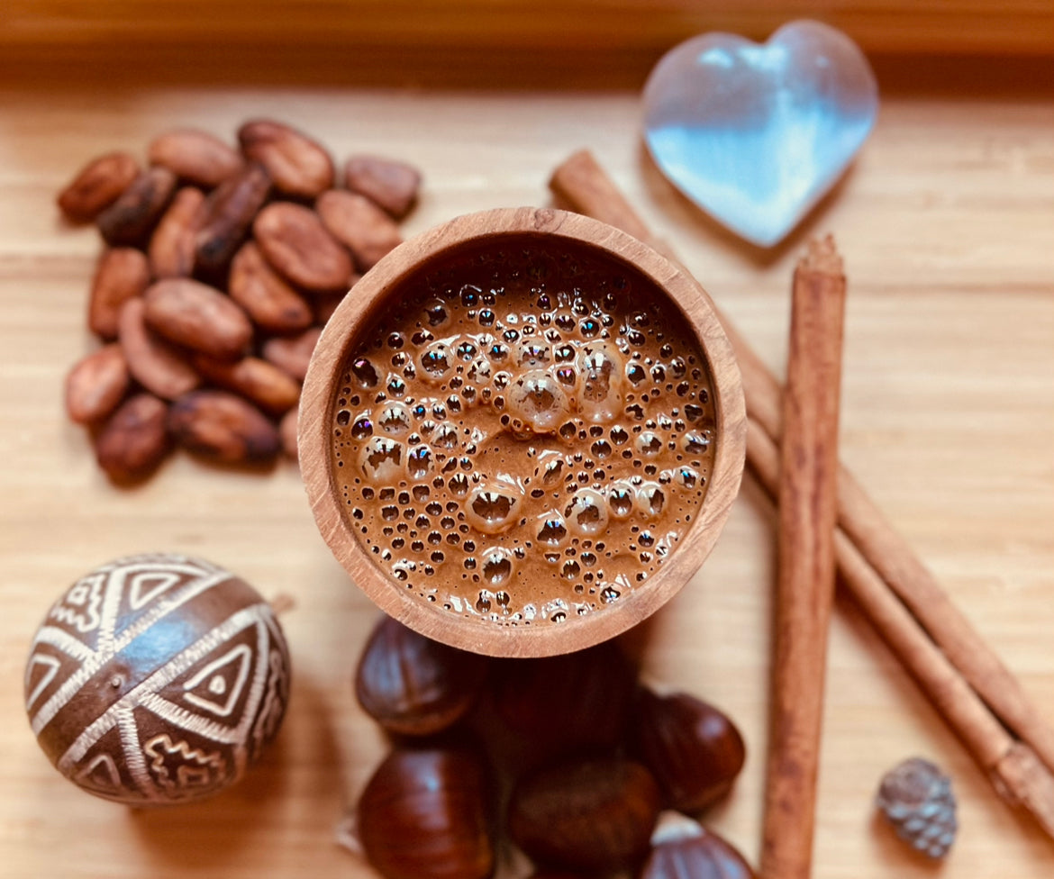 Taza de cacao con elementos naturales como canela, semillas, castañas, piedra dorma de corazón, sobre madera