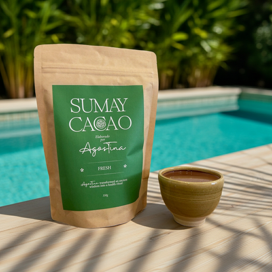 Bolsa de cacao ceremonial Fresh de Sumay Cacao junto a un vaso de cacao con hielo, limón, jengibre, vainilla y lemongrass, sobre mesa de madera junto a una piscina en un ambiente veraniego.
