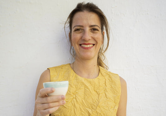 Isa Boyd con taza de cerámica en la mano sobre fondo blanco