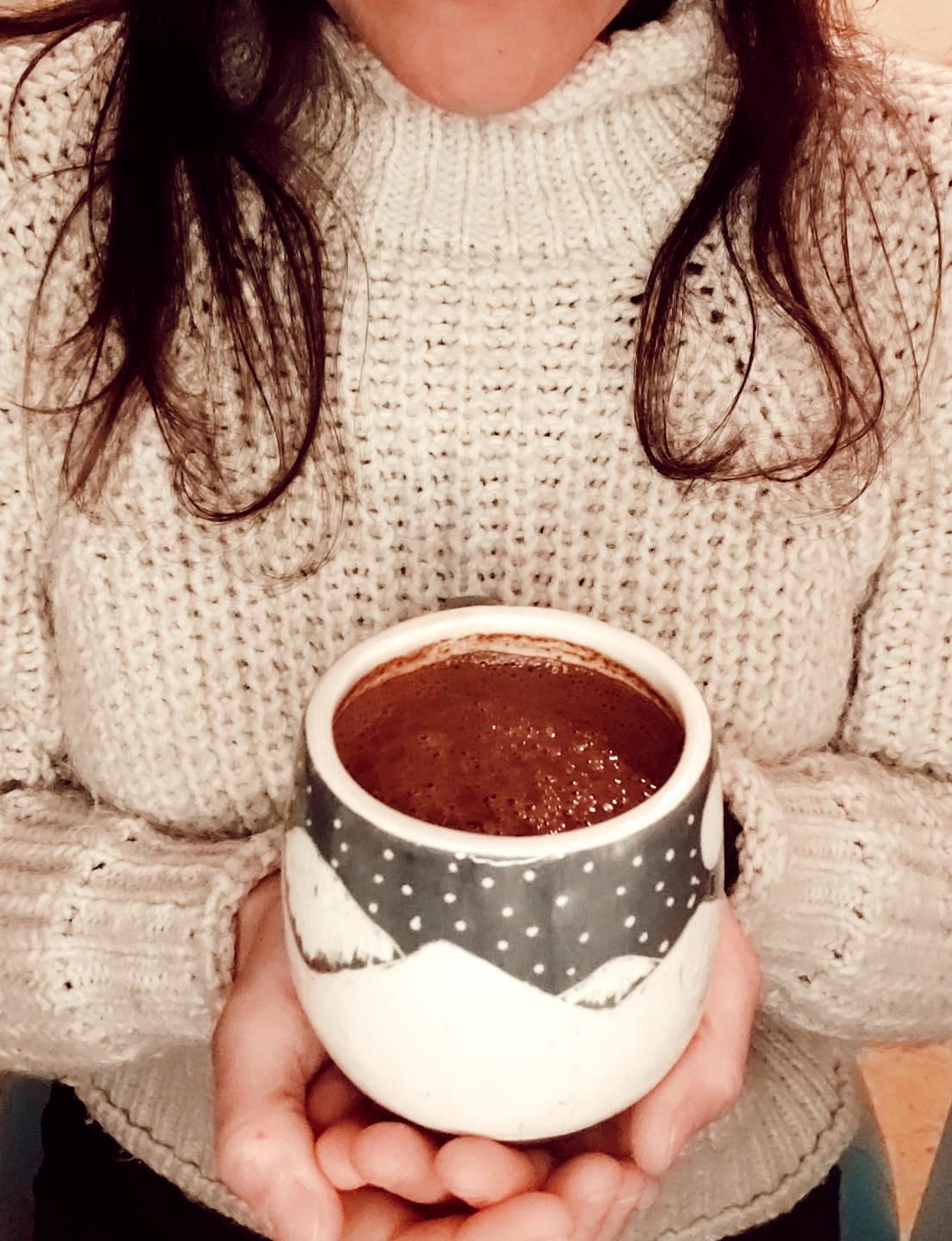 Taza de cacao ceremonial puro sostenida en las manos durante un ritual diario con Sumay Cacao