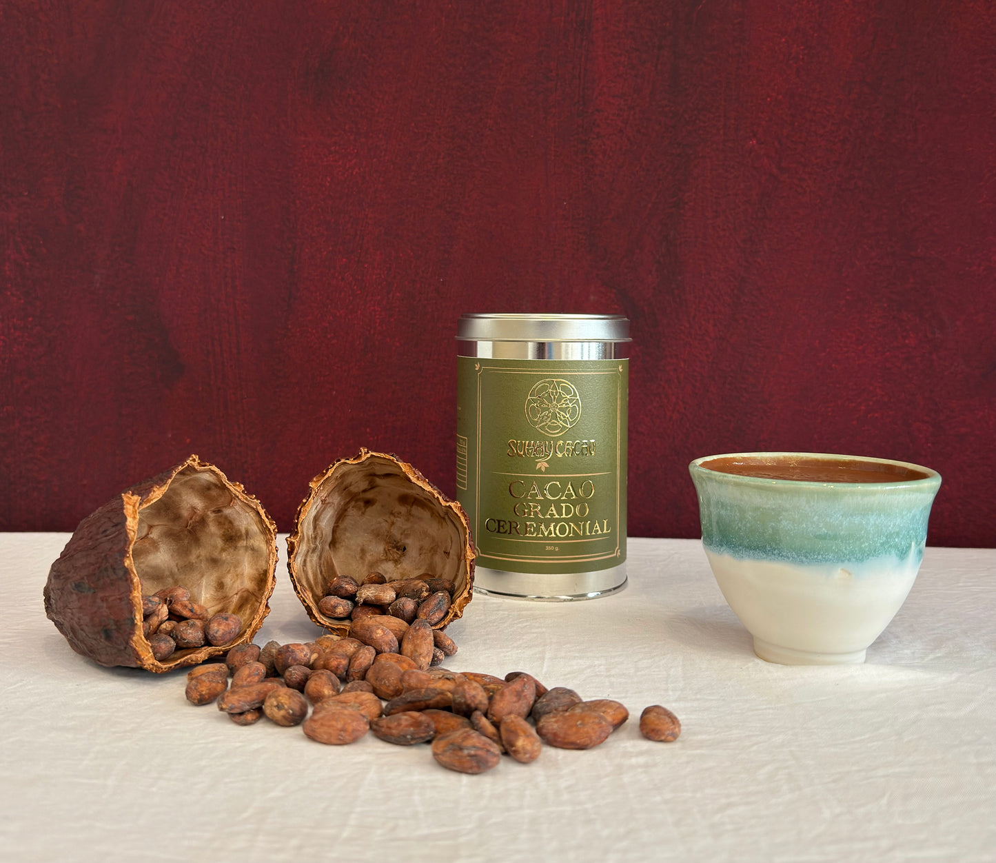 Lata de cacao ceremoanil Sumay sobre mesa blanca con taza de cacao y semillas en fruto de cacao seco