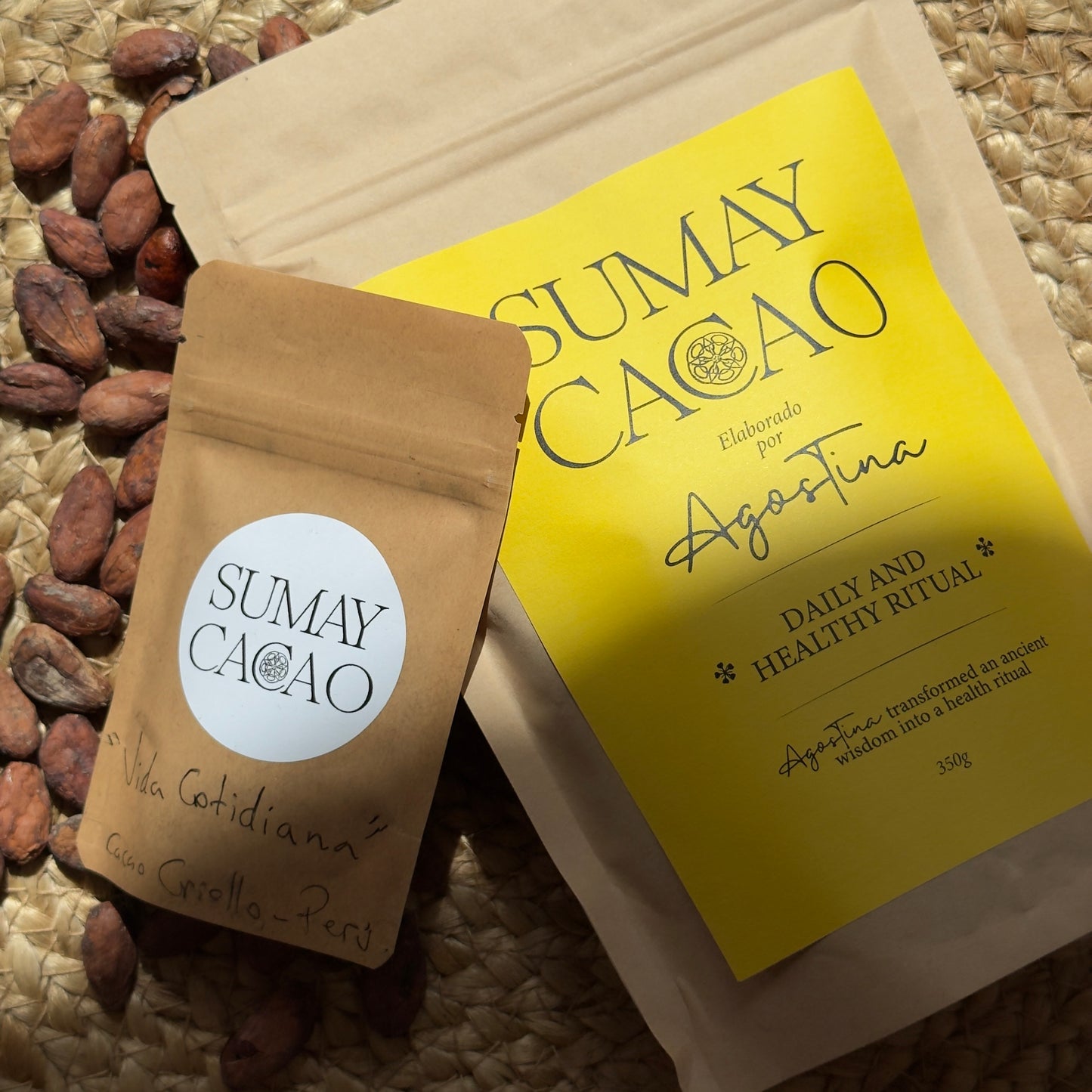 Paquete de cacao grande y otro pequeño sobre mesa de madera con semillas y luz solar