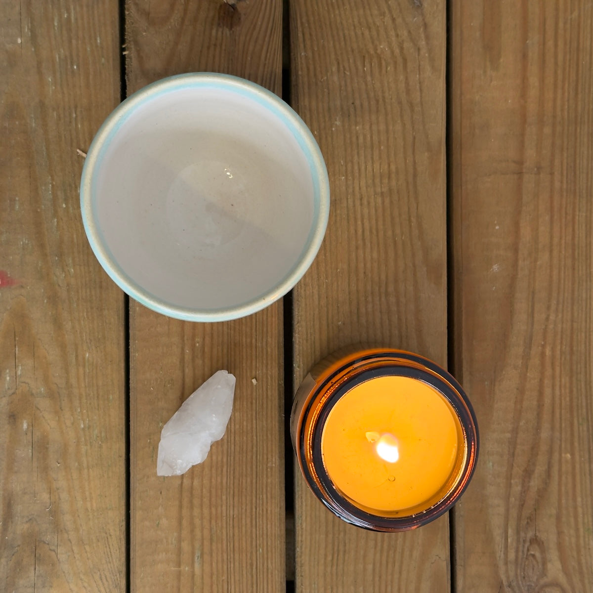 Vela, cuarzo y taza minimalista sobre fondo de madera.