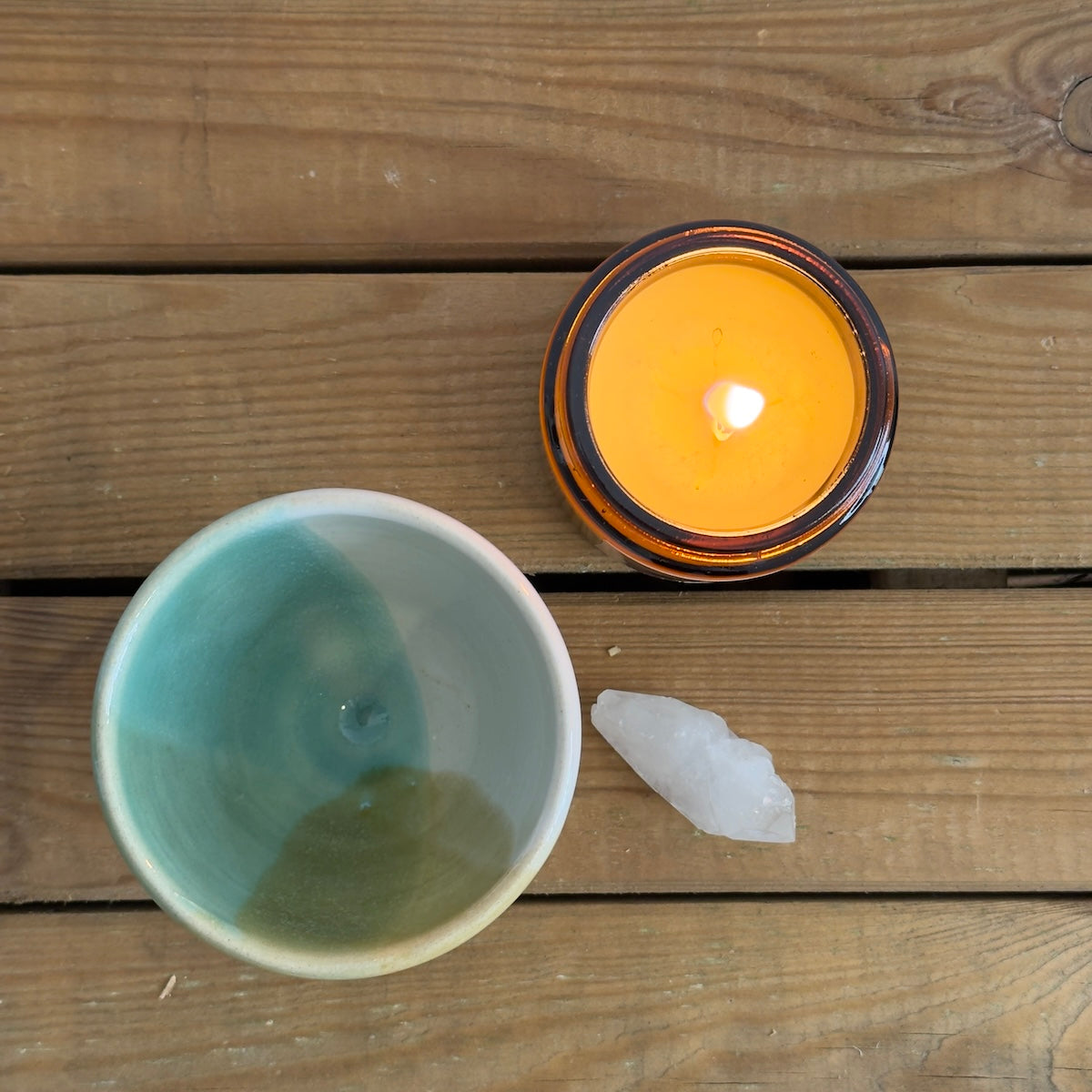 Taza artesanal hecha por Isa Boyd para Sumay Cacao con vela y cuarzo sobre mesa de madera.