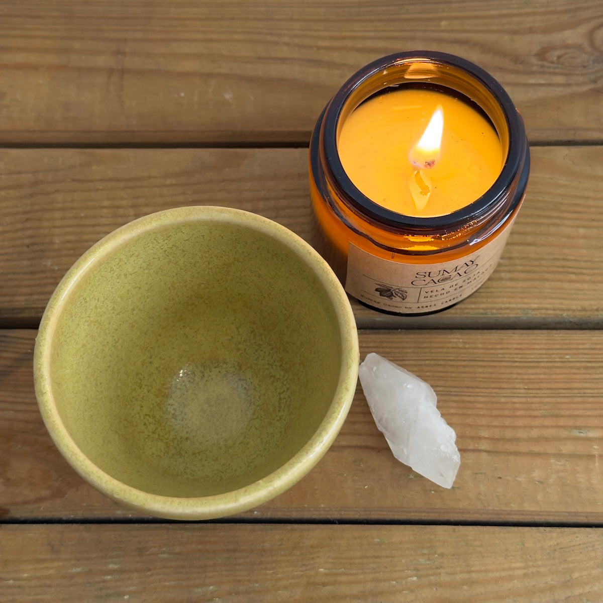 Mesa de madera con taza artesanal, diseño único, vela y cuarzo.