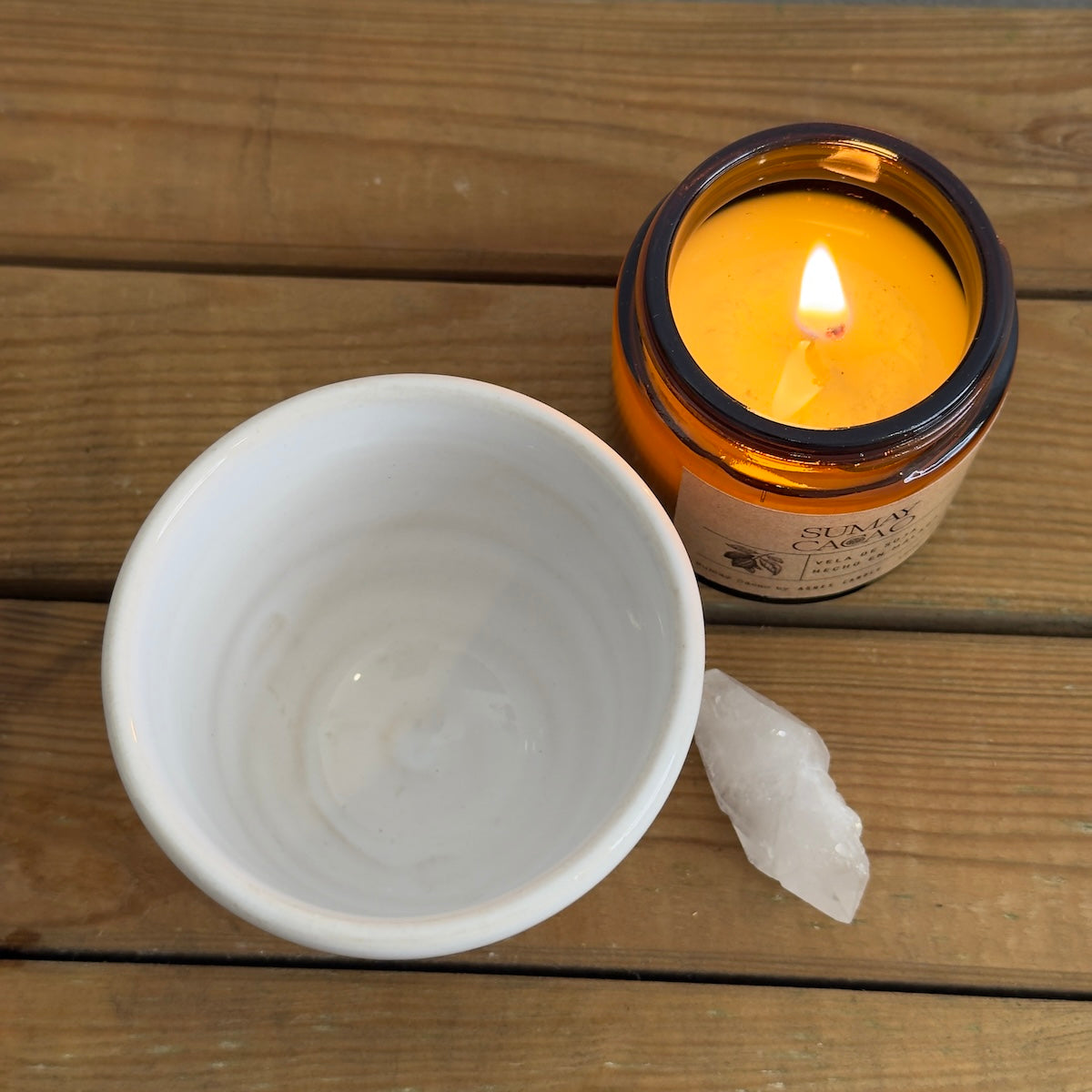 Taza blanca vista aerea con vela y cuarzo sobre mesa de madera.