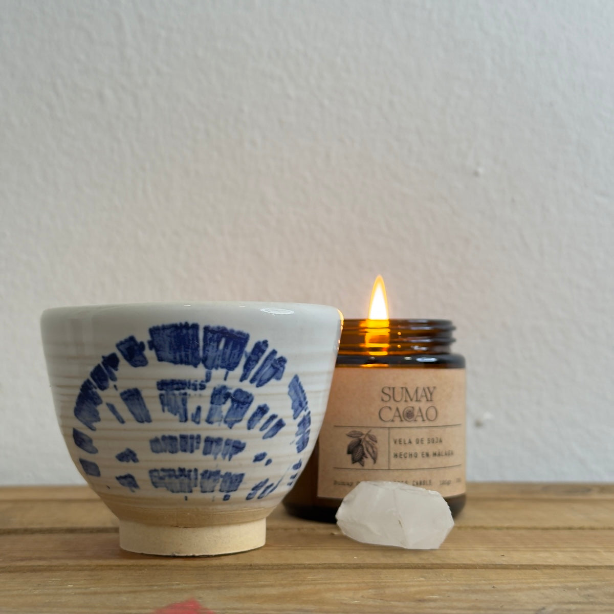 Taza de cerámica artesanal "abanico" con cuarzo y vela encendida.