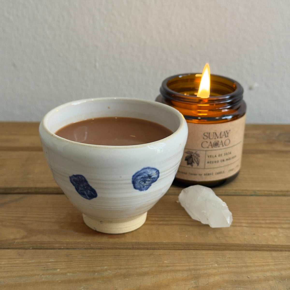 Cacao ceremonial en taza artesanal con vela y cuarzo.