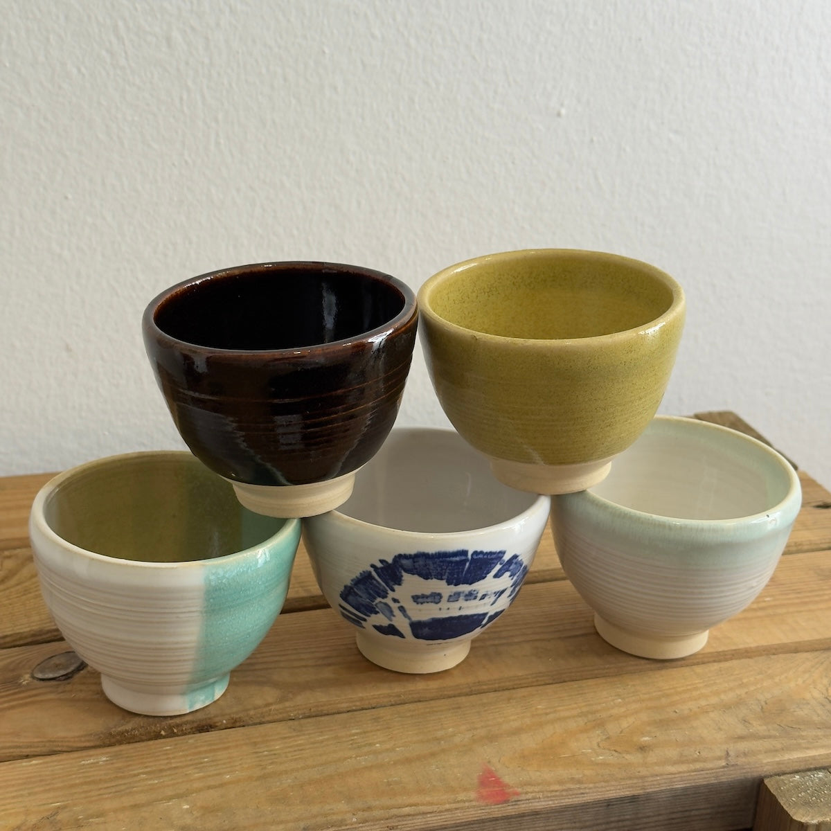 Tazas artesanales hechas por Isa Boyd sobre cajon de madera.