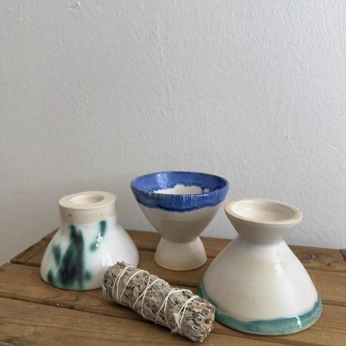 Copaleras artesanales sobre mesa de madera con salvia y fondo blanco.