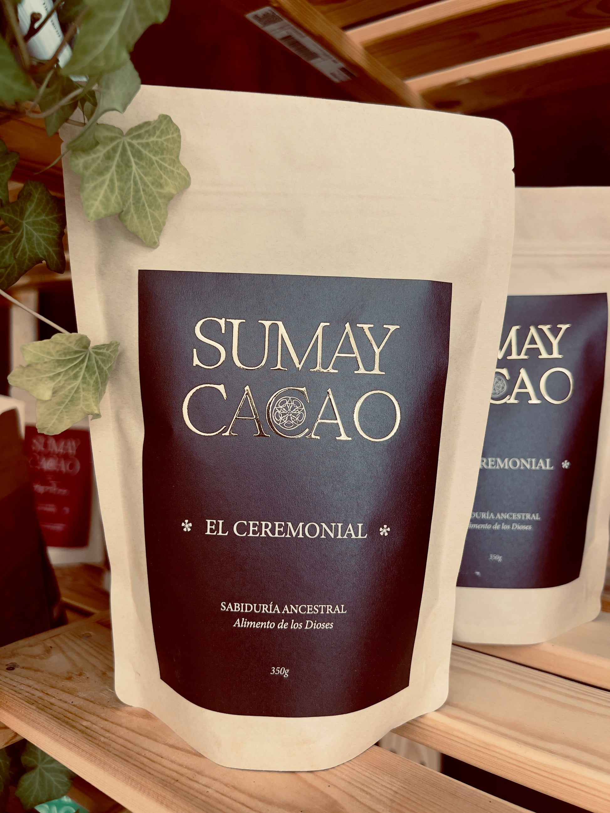 Paquete de cacao ceremonial Sumay sobre estante de madera y con algunas hojas verdes decorando