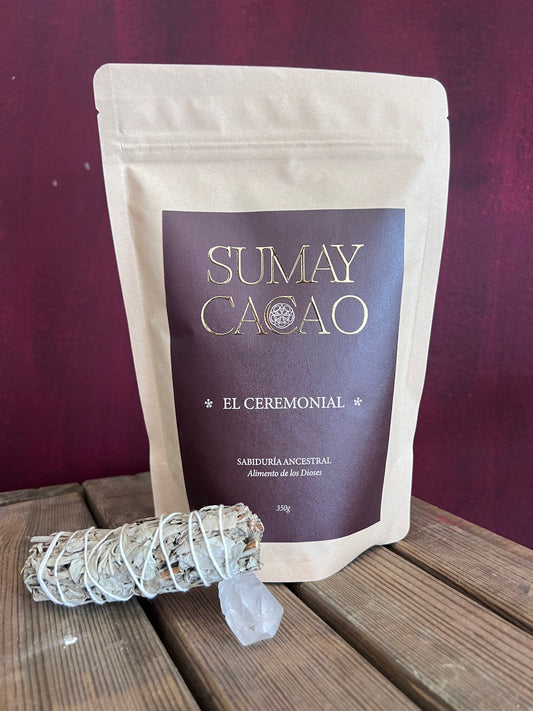 Bolsa de cacao ceremonial Sumay acompañada por un atado de salvia y un cuarzo, sobre cajón de madera con fondo rojizo.