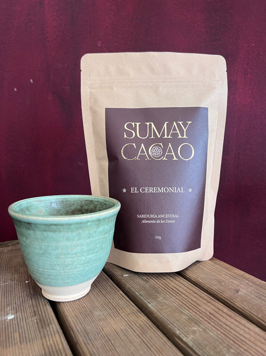 Taza de cerámica artesanal con paquete de cacao ceremonial Sumay sobre cajón de madera y fondo pared roa oscura