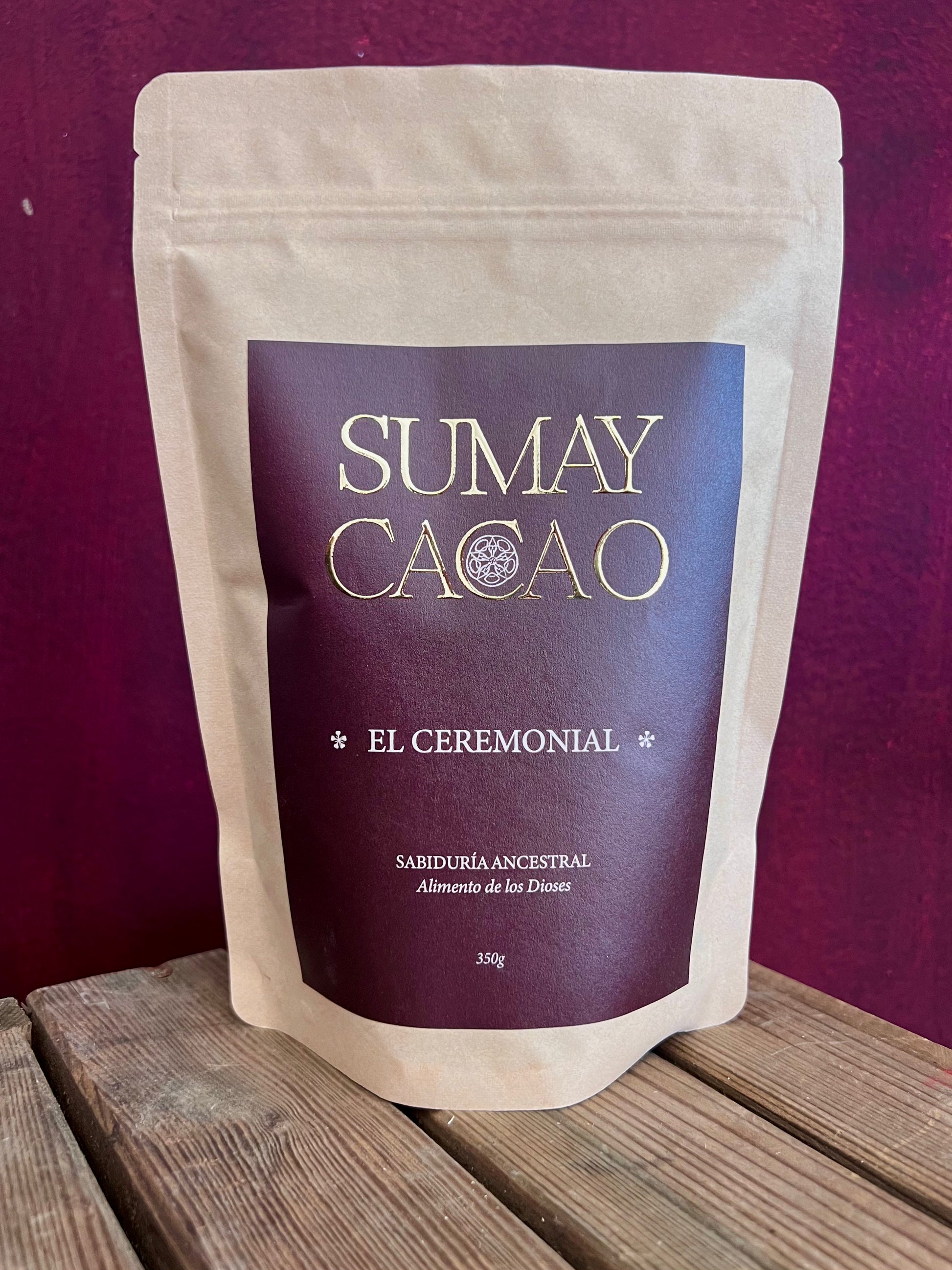 Bolsa de cacao ceremonial Sumay sobre cajon de madera y fondo rojo escuro.