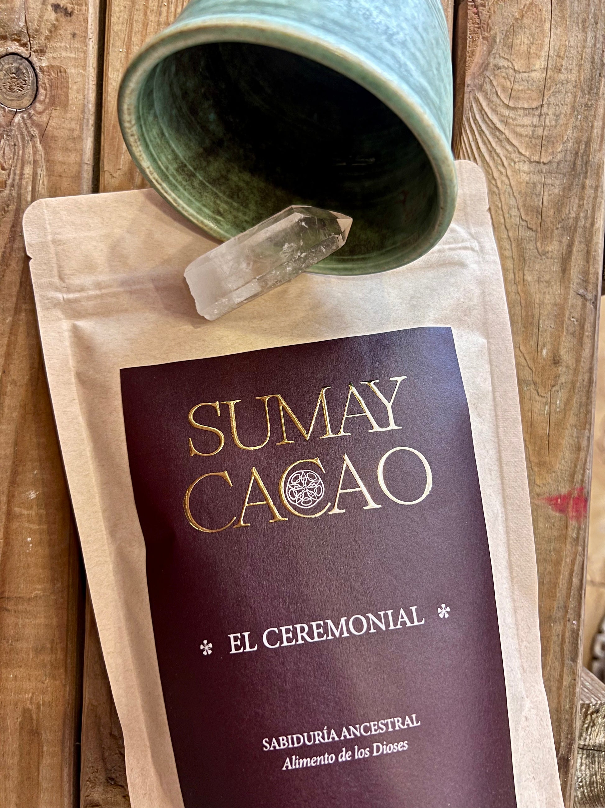 Taza artesanal de cerámica junto a un cuarzo y un paquete de cacao ceremonial Sumay para rituales.