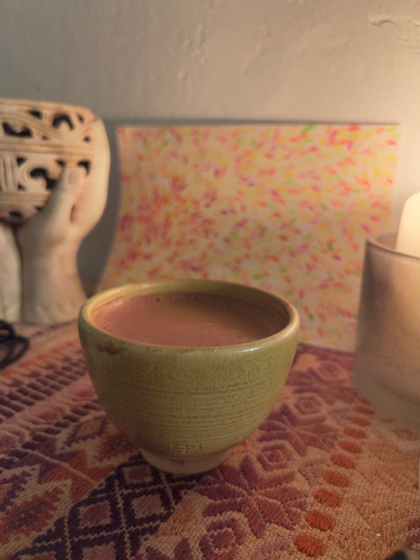 Taza artesanal de cerámica "sol de otoño" con cacao ceremonial en altar con vela, copalera  y dibujo detrás