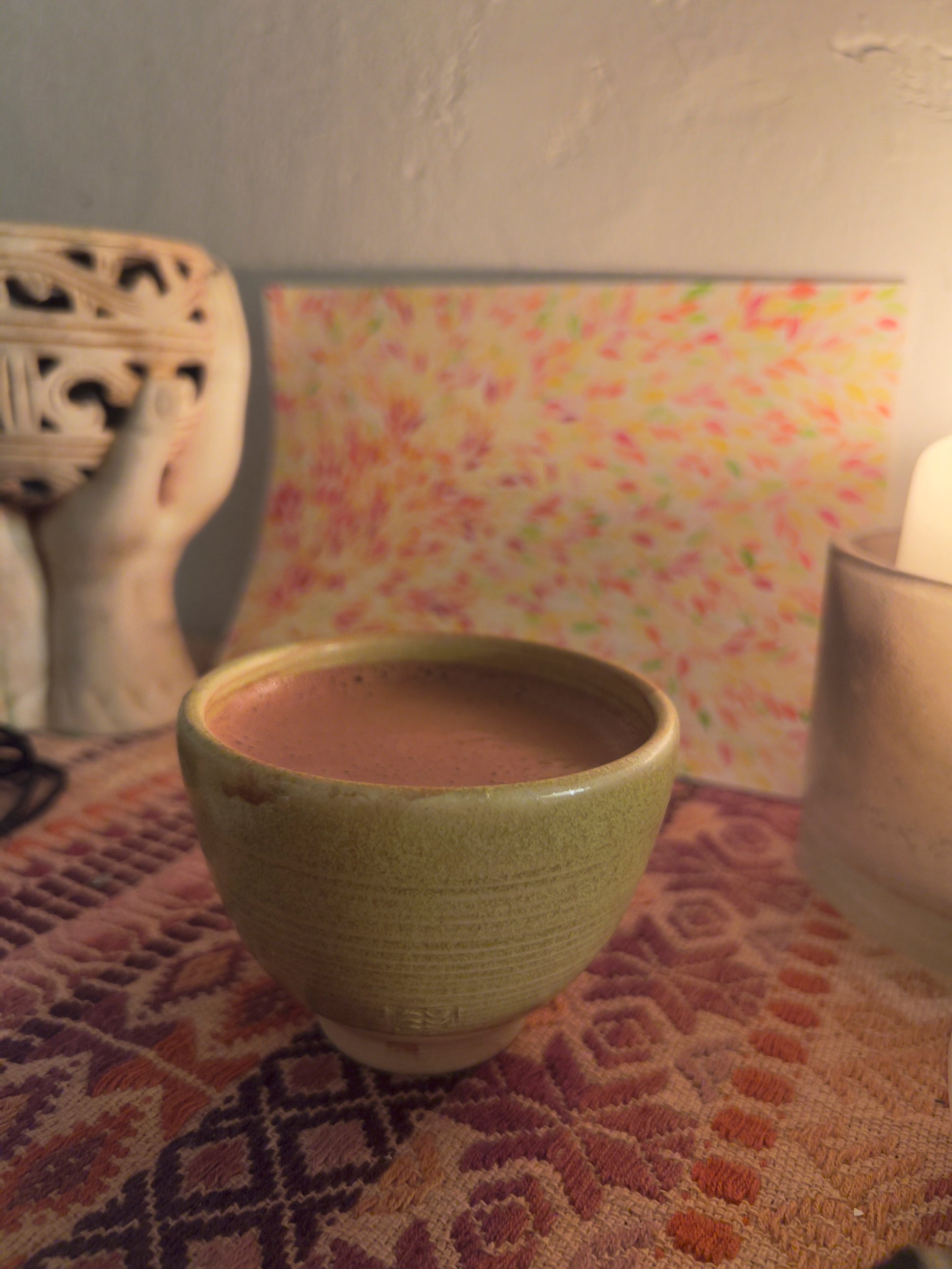 Taza artesanal de cerámica "sol de otoño" con cacao ceremonial en altar con vela, copalera  y dibujo detrás