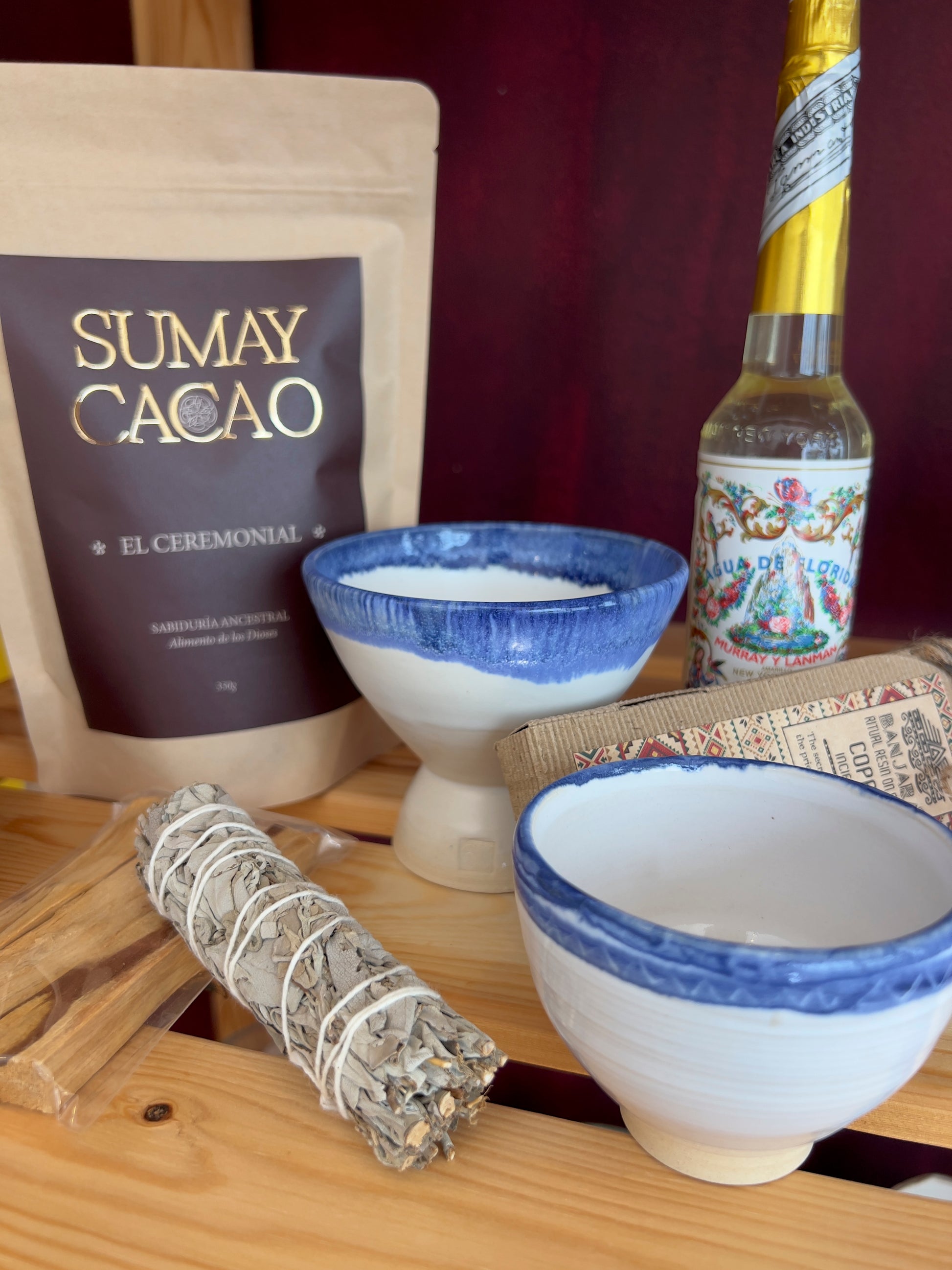 Taza y copalera artesanales hechas por Isa Boyd a juego, con paquete cacao ceremonial Sumay y elementos de purificación sobre estante de madera.