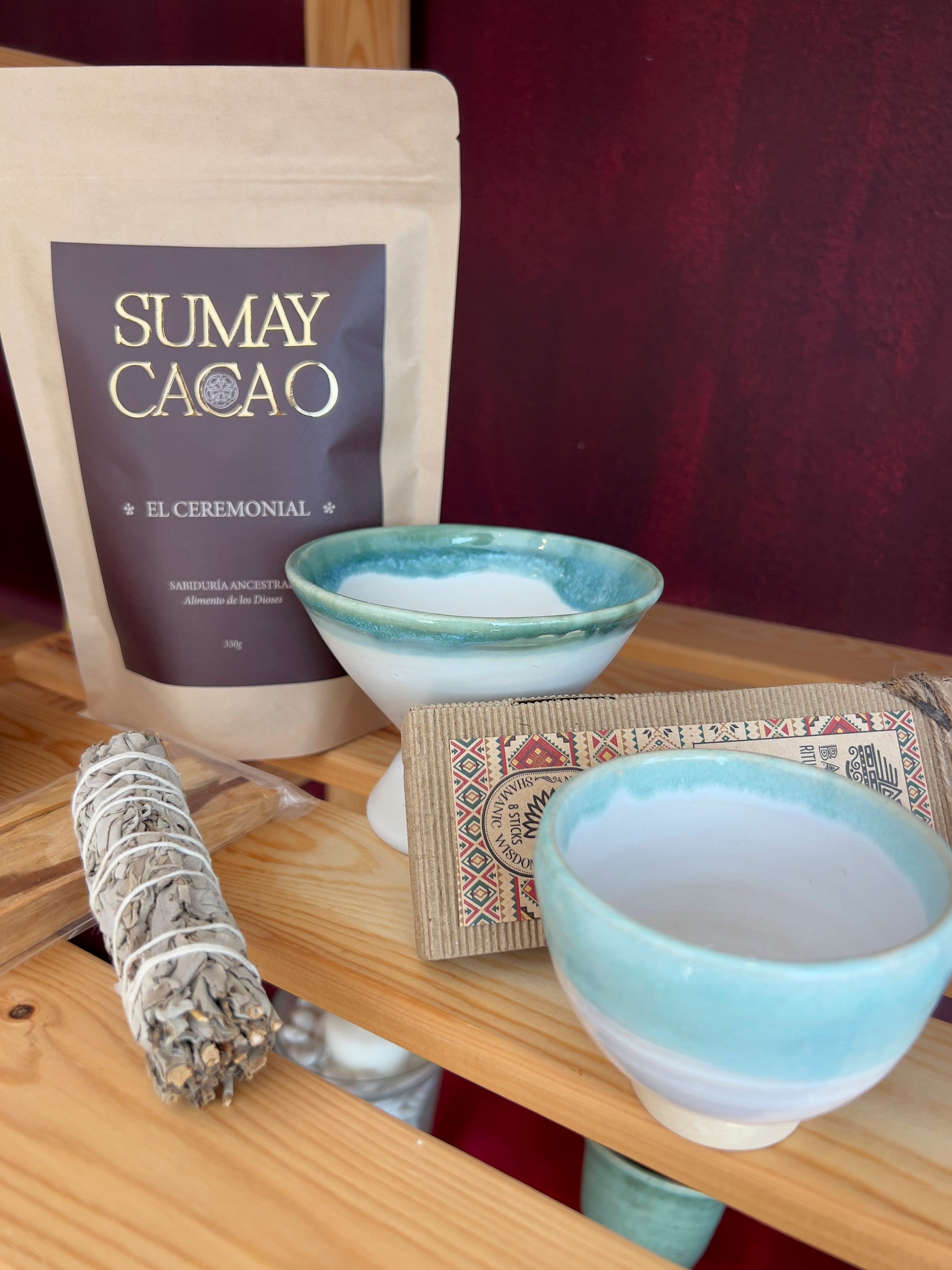 Taza y copalera de cerámica artesanal, Isa Boyd, a juego con turquesa en el borde, sobre estante de madera con elementos de limpieza enrgética.