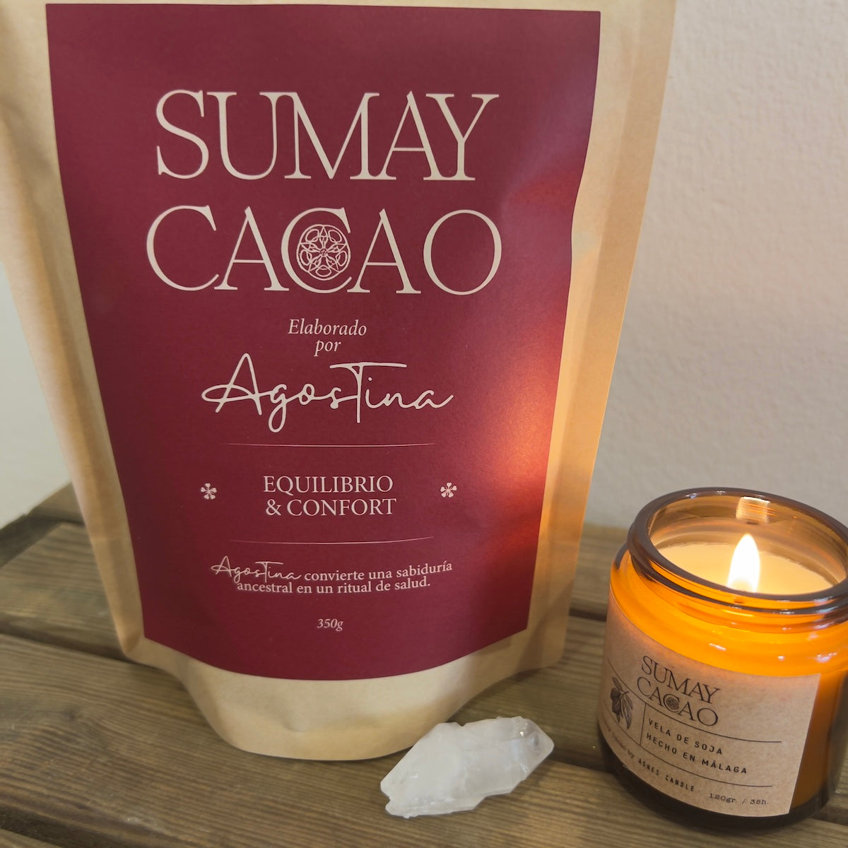 Paquete de cacao ceremonial con vela y cuarzo sobre mesa de madera.