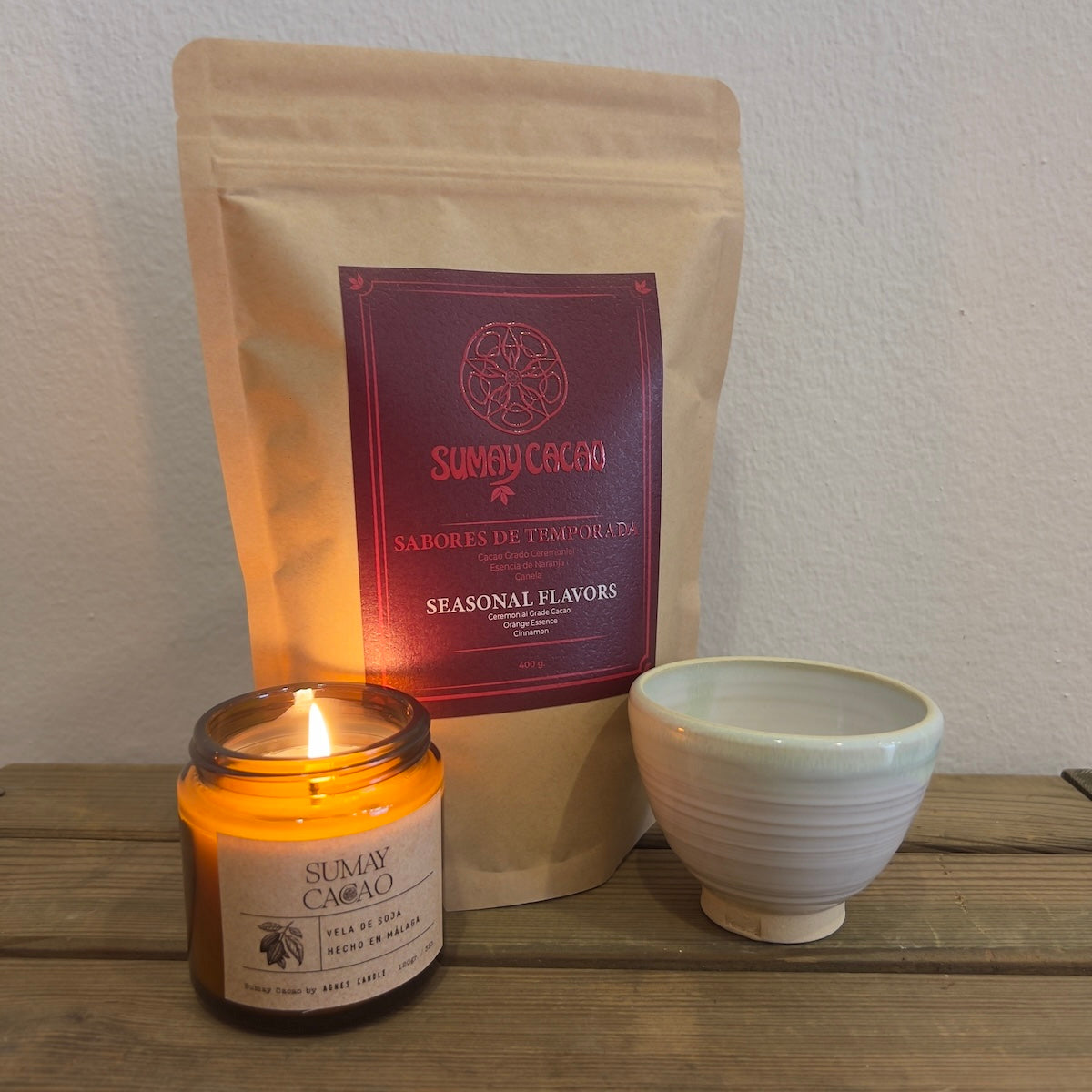 Sabores de temporada 400g paquete cacao picado con taza artesanal y vela de soja, fondo blanco.