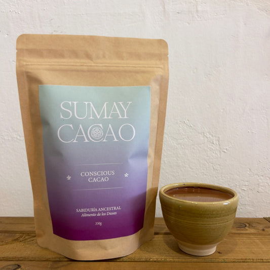 Paquete cacao ceremonial Conscious Cacao con taza artesanal de Isa sobre fondo neutro