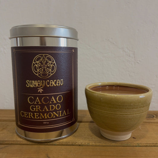 Lata cacao ceremonial Sumay con taza artesanal de Isa Boyd de cacao sobre fondo neutro