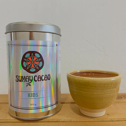 Lata cacao kids Sumay con taza de cacao artesanal sobre fondo neutro