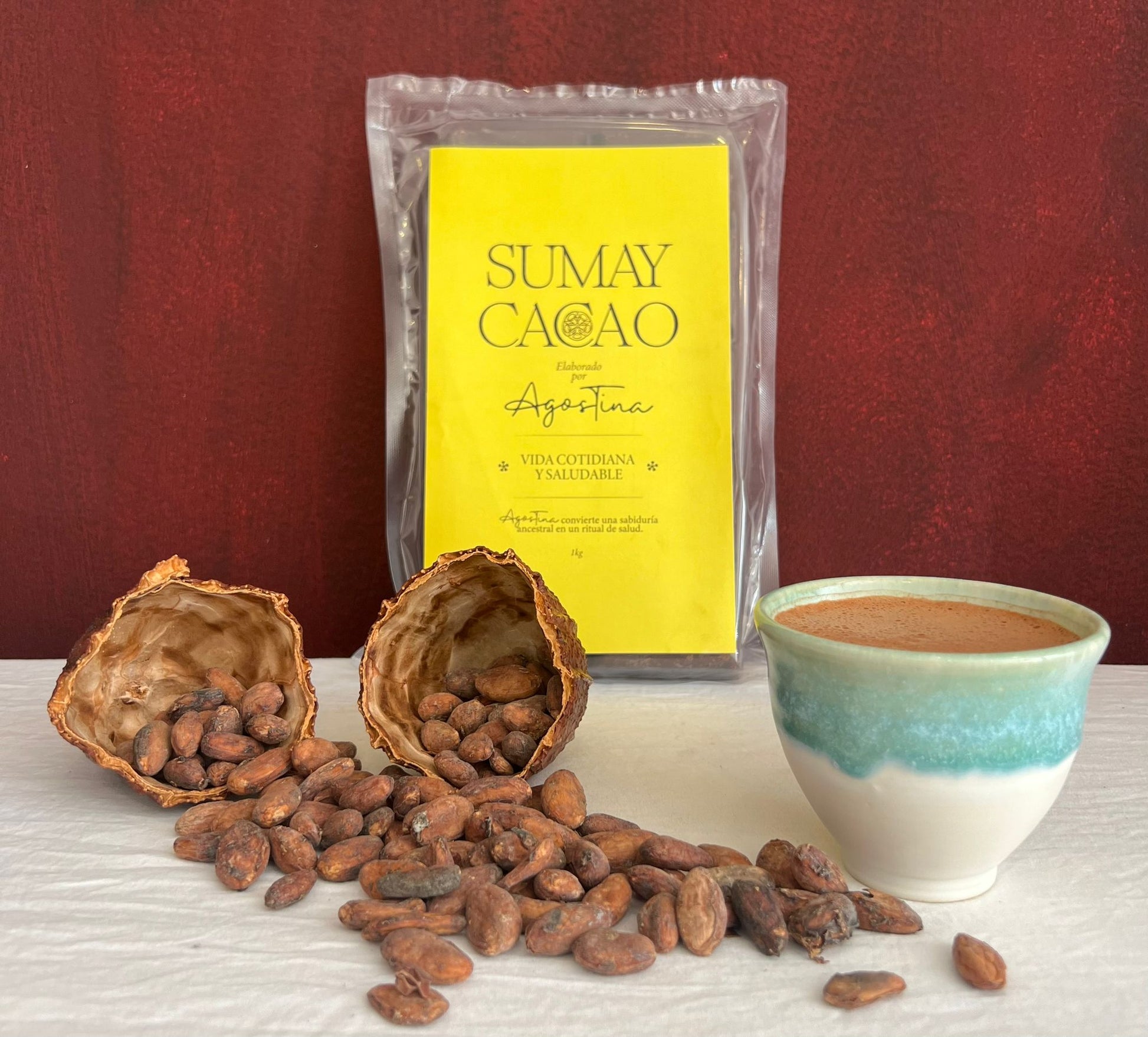 Paquete kilo Vida Cotidiana a y Saludable Sumay cobre mesa blanca con taza de cacao. semillas y cascara fruto sobre fondo rojizo