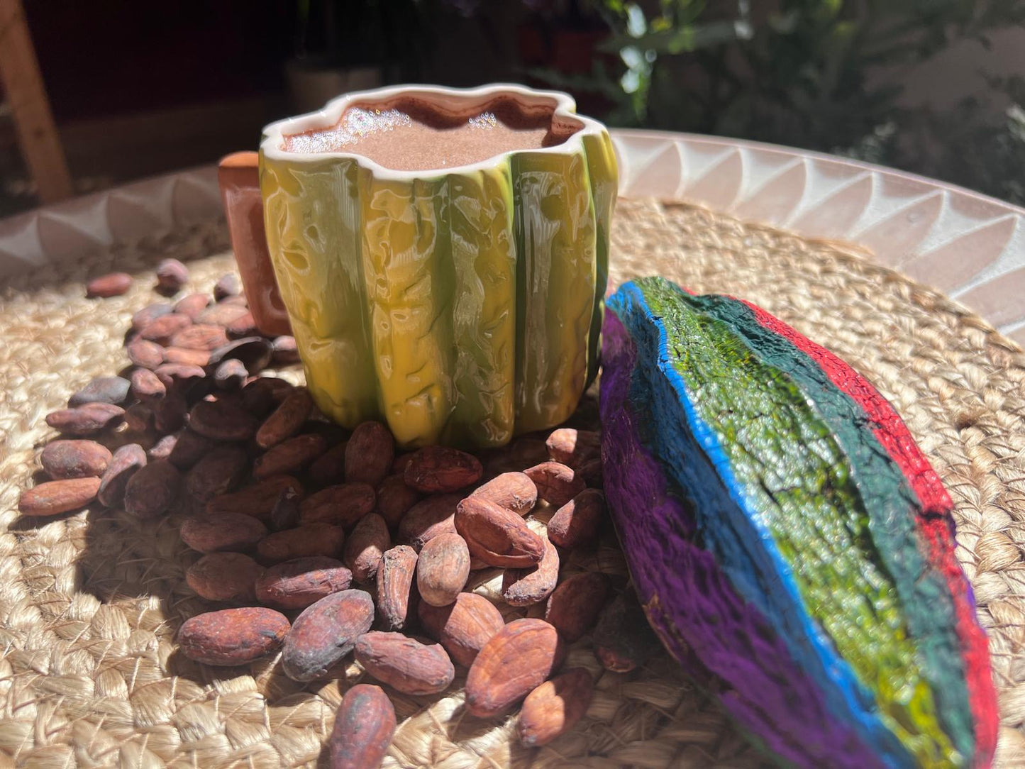 Taza de cacao kids con forma de fruto cacao y fruto de colores con semillas rodeando la taza