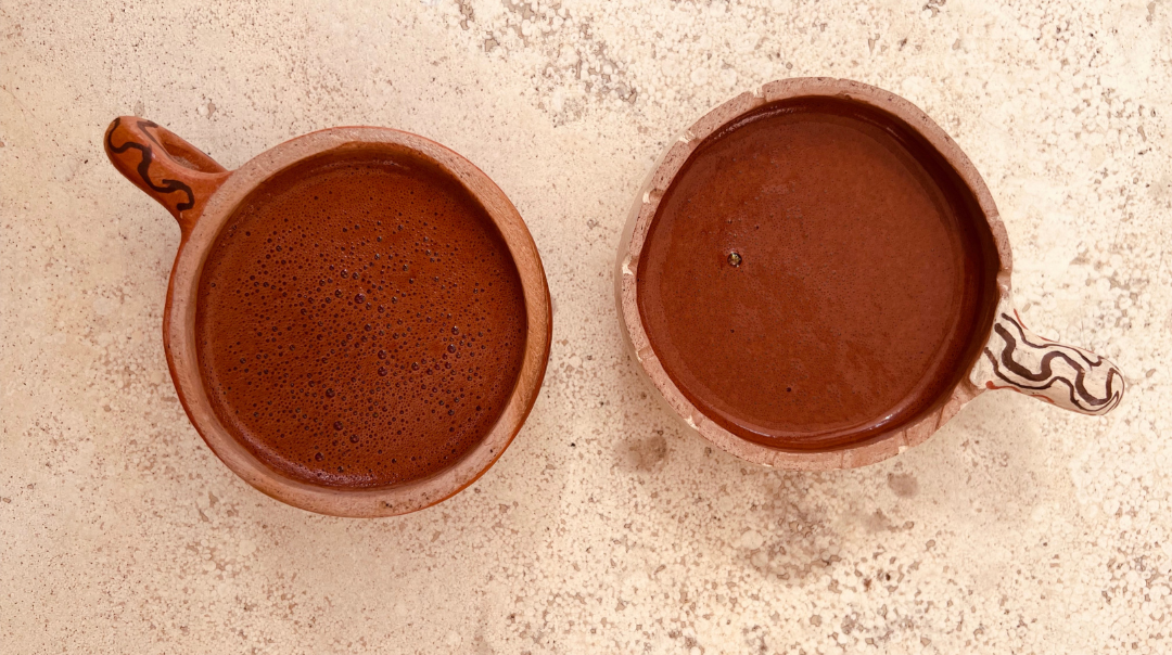 Tazas de barro artesanales con cacao ceremonial sobre mesa de mármol